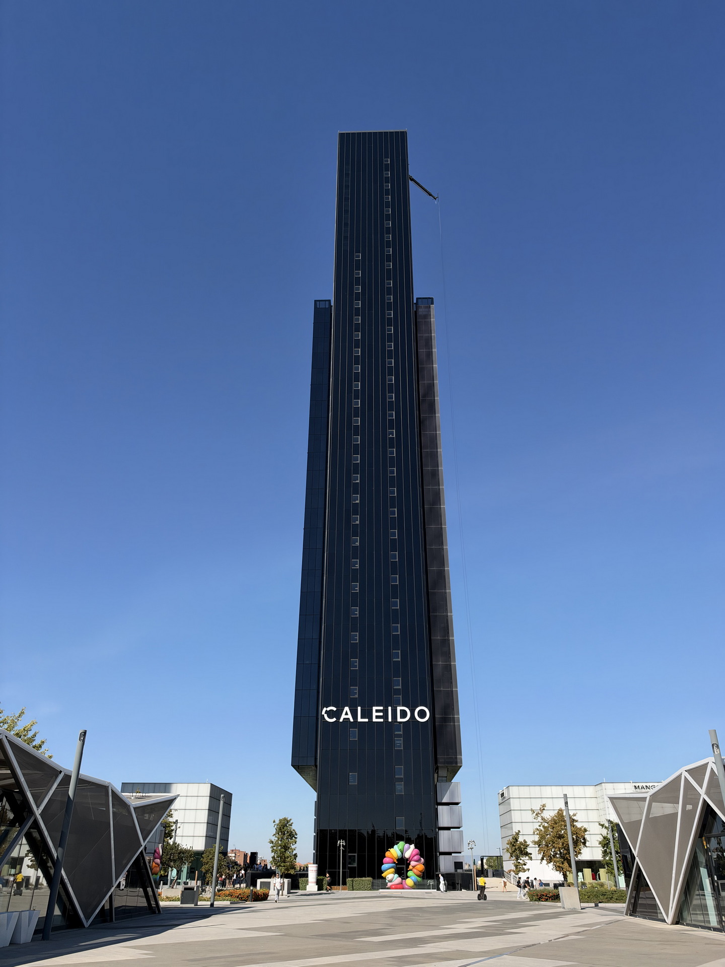 Edificio Caleido, rascacielos moderno en Madrid bajo un cielo despejado, destacando por su diseño vertical y elegante.