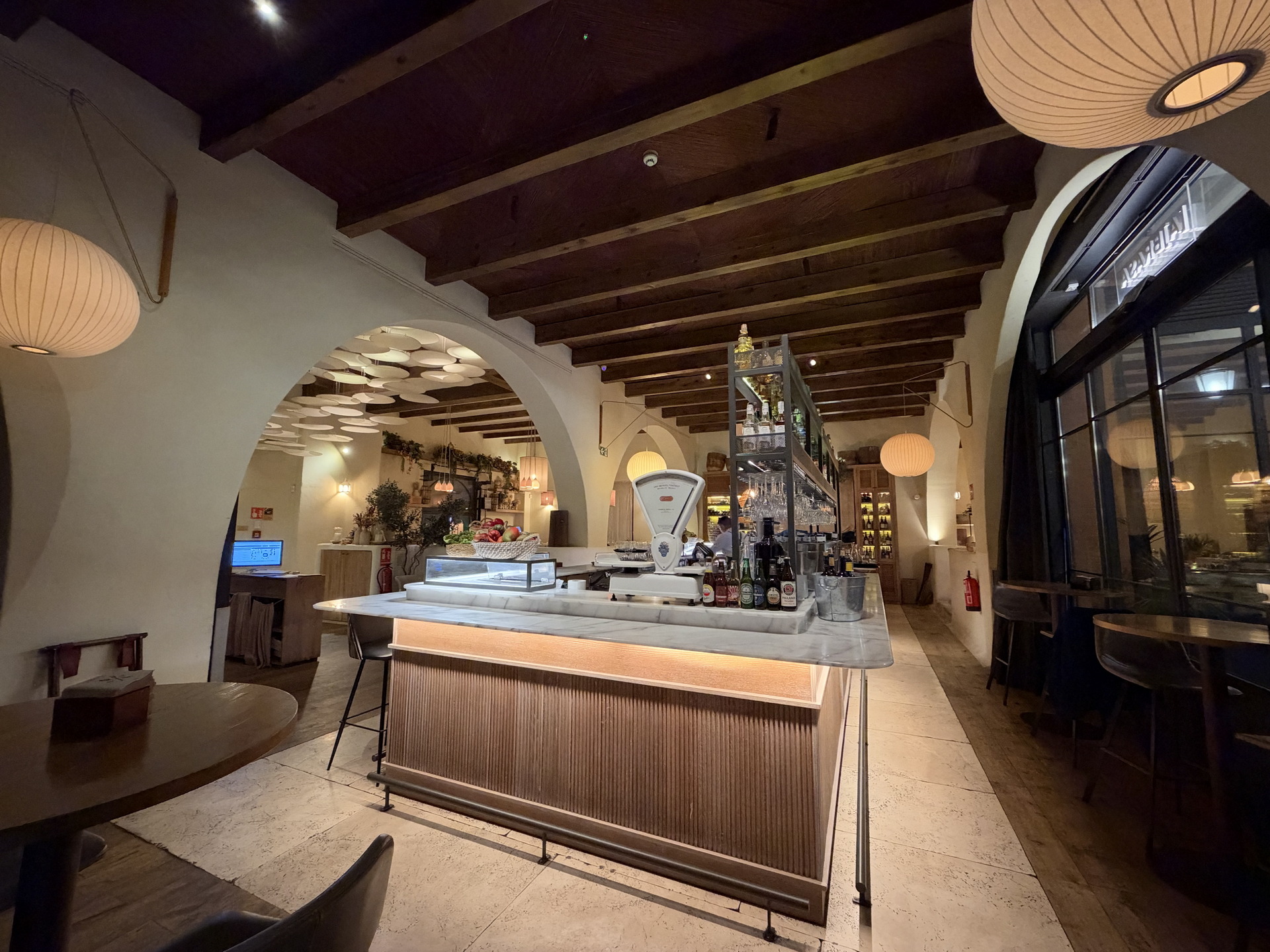 Interior acogedor de un restaurante con barra iluminada, techo de vigas de madera y lámparas colgantes.