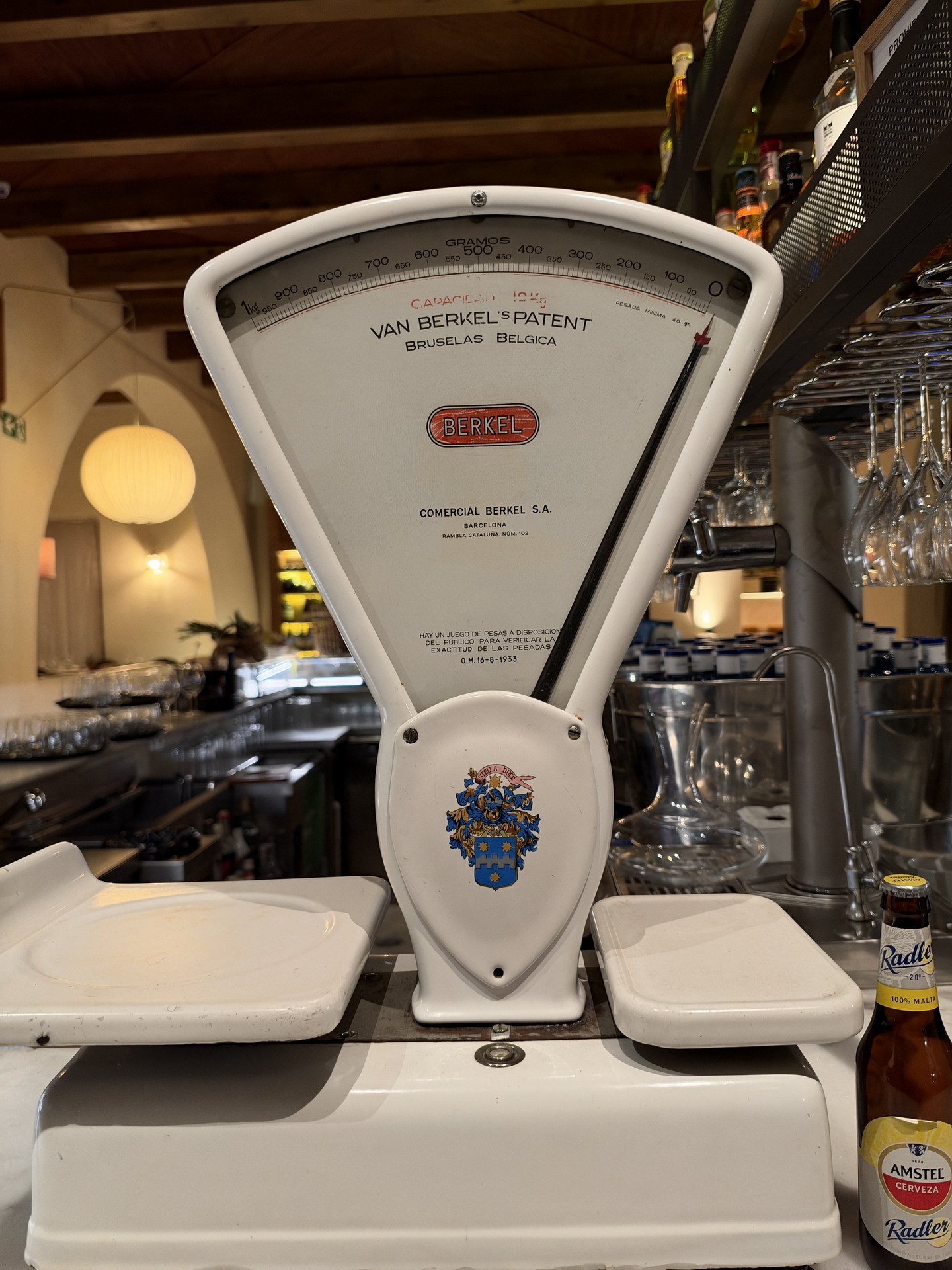 Balanza antigua de Berkel en un bar, junto a una botella de cerveza Amstel Radler. Ambiente acogedor y vintage.