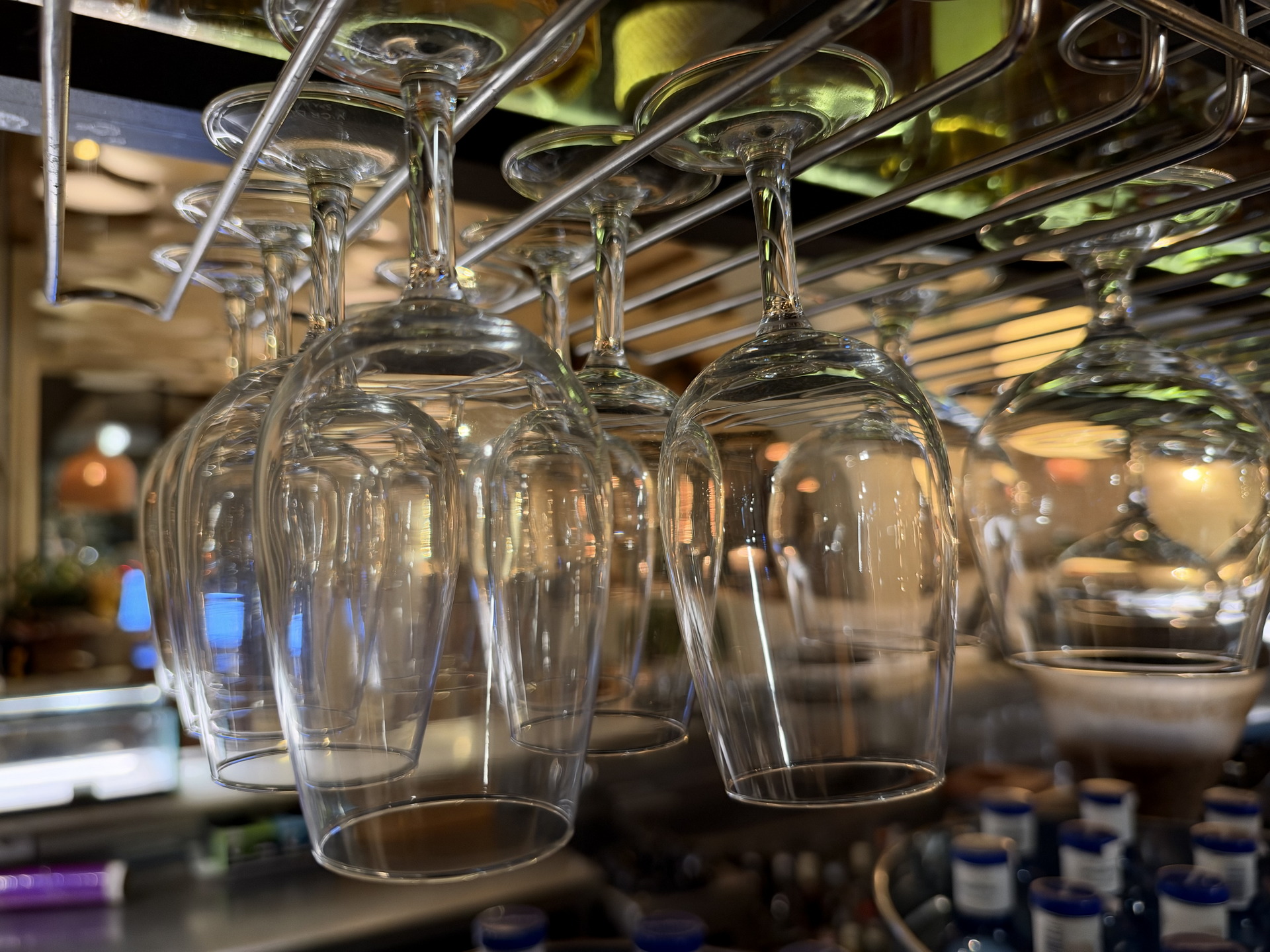 Copas de vino colgadas boca abajo en un bar elegante con iluminación cálida y ambiente acogedor.