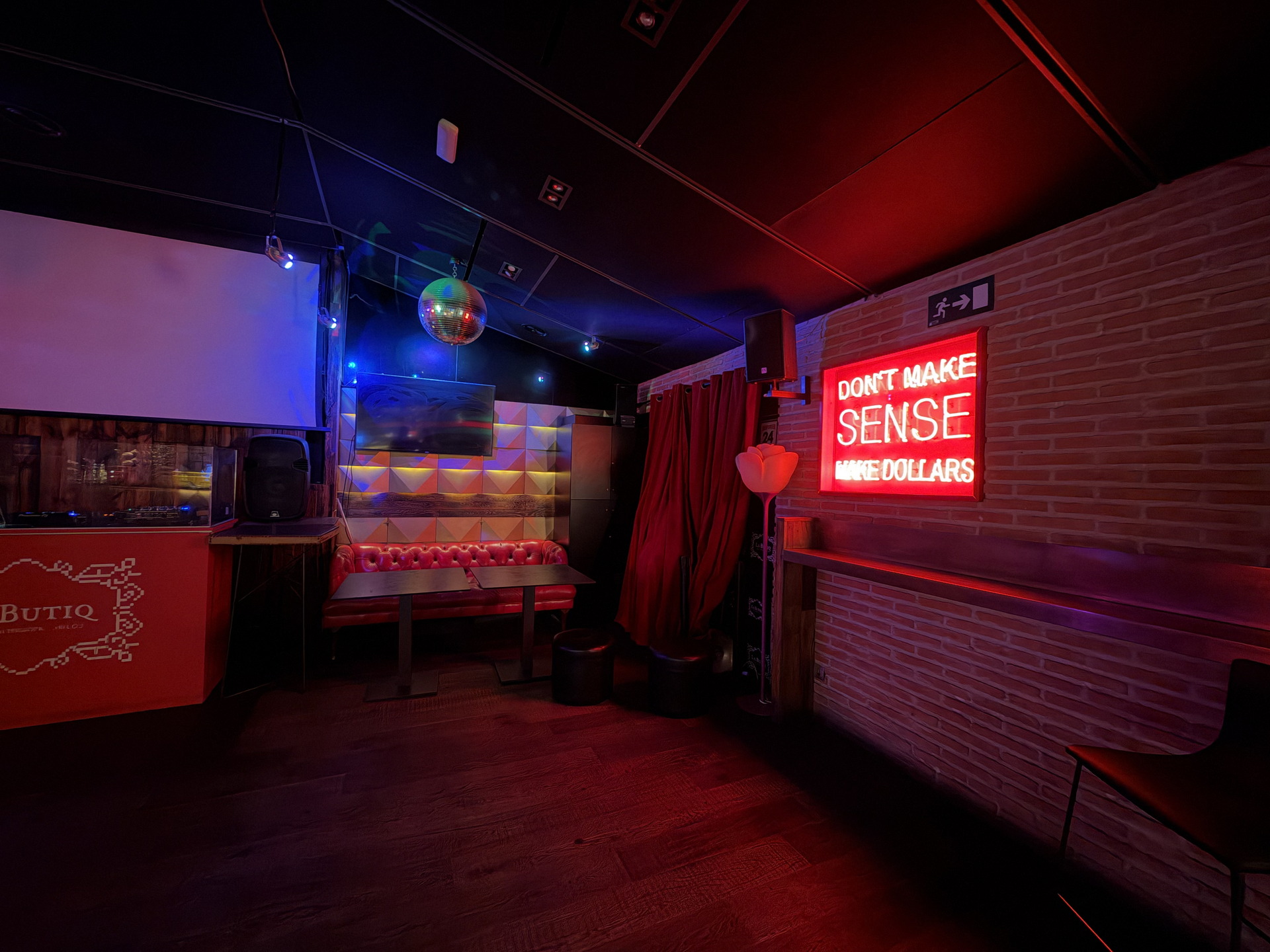 Interior de club nocturno con letrero de neón rojo que dice Don't make sense, make dollars. Ambiente moderno.