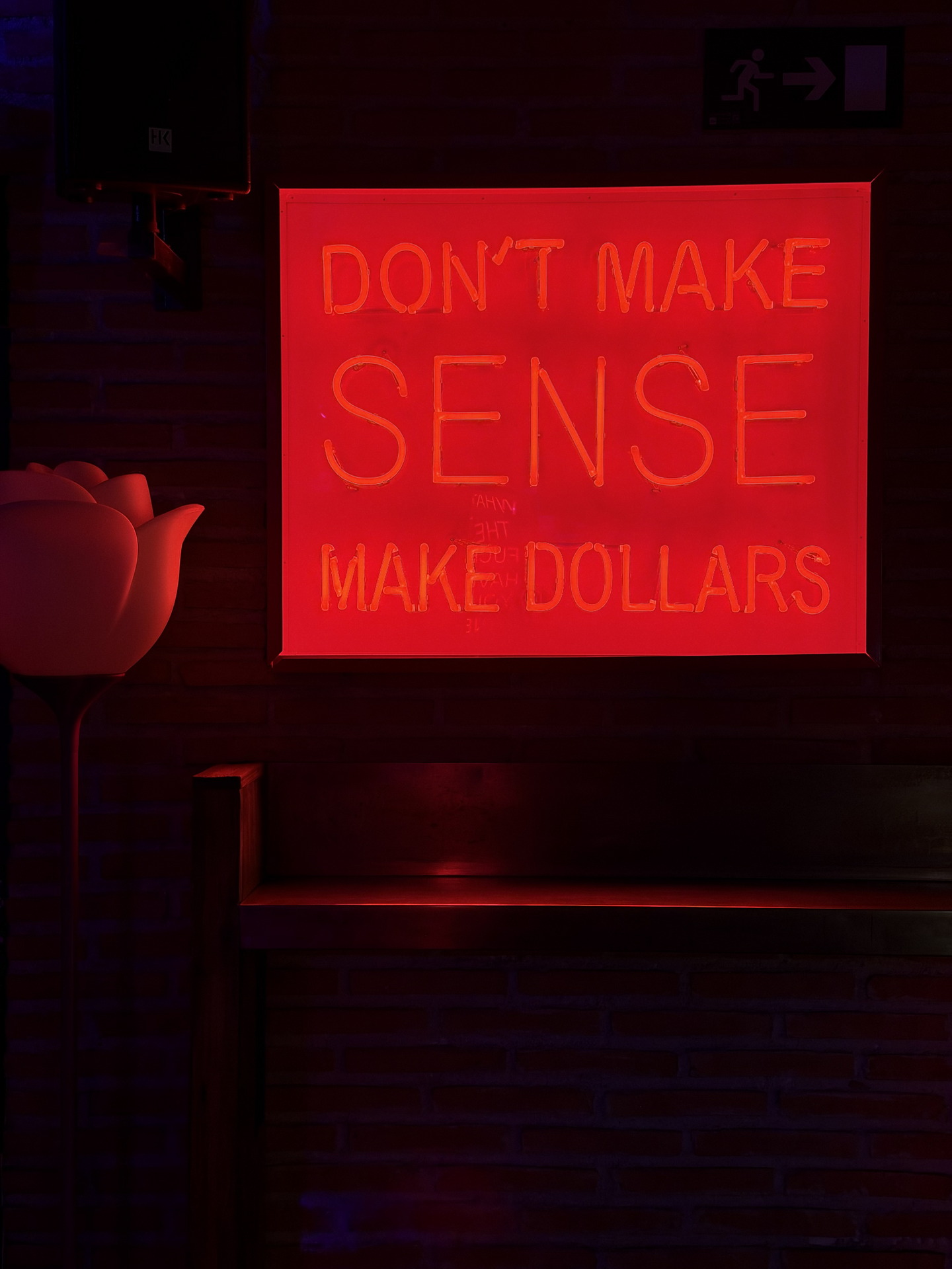 Señal de neón roja en pared de ladrillo: Don't make sense, make dollars. Frase inspiradora de negocios.
