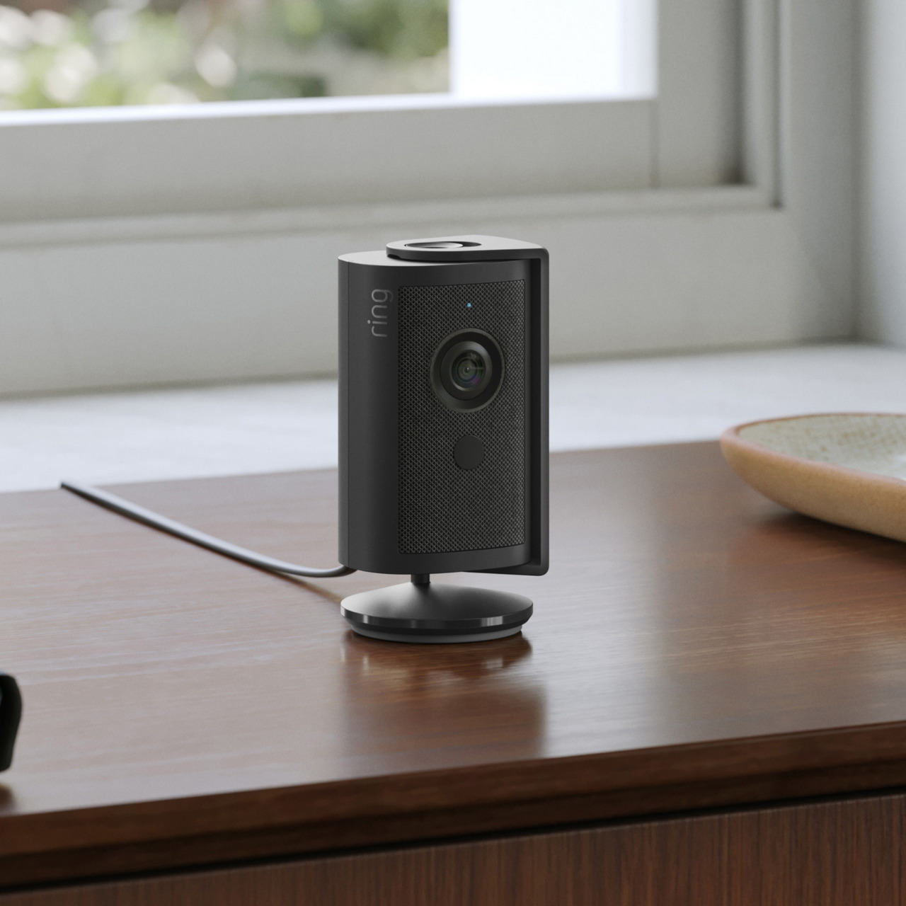 Ring Indoor Camera 4K negra sobre un mueble junto a una ventana